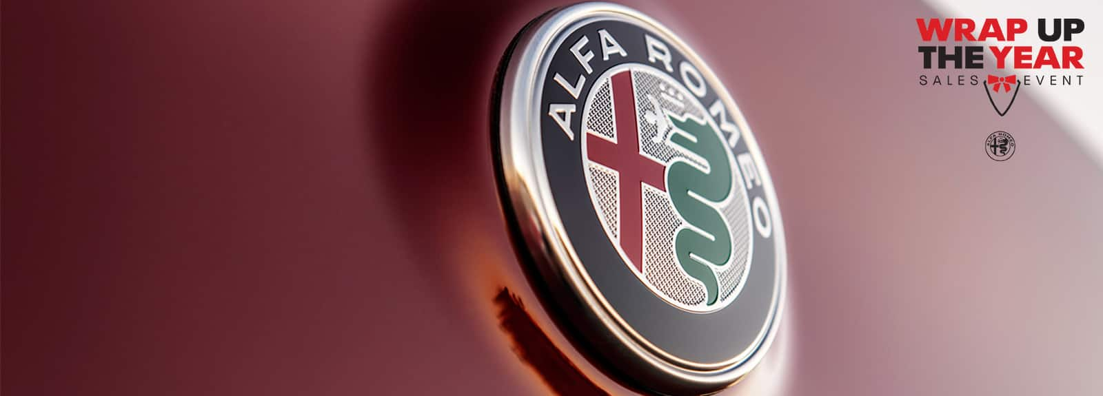 A close-up of the Alfa Romeo badge. Wrap Up The Year Sales Event logo.